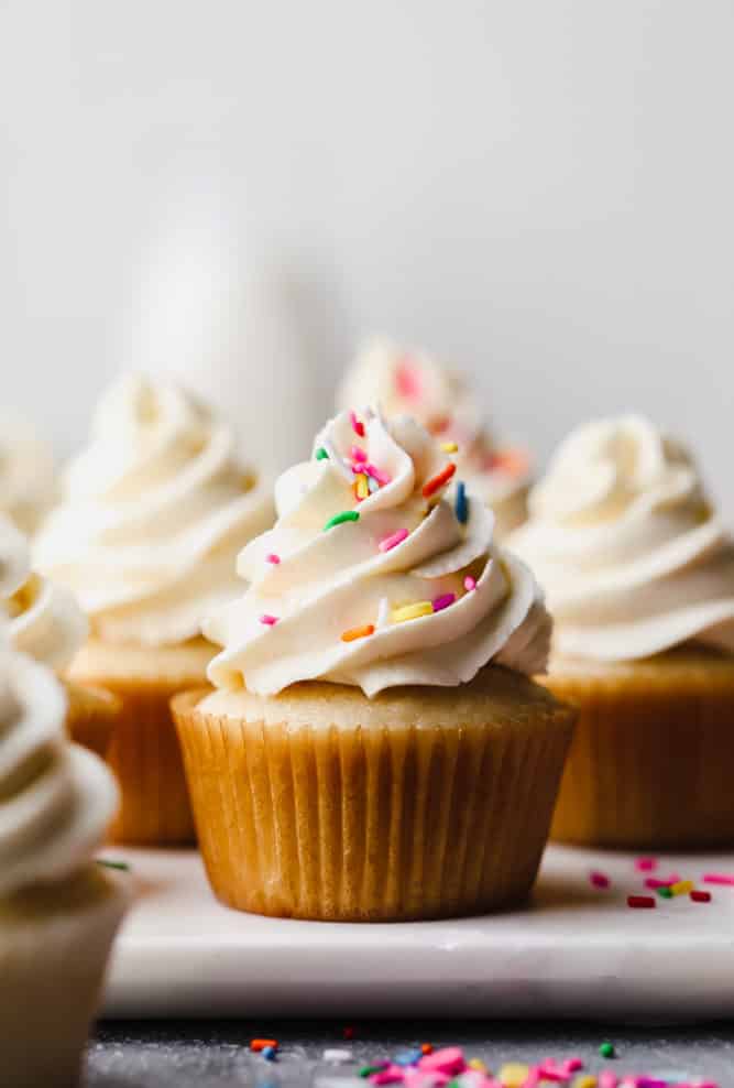 one cupcake in focus with sprinkles, more in the backyard that are blurry