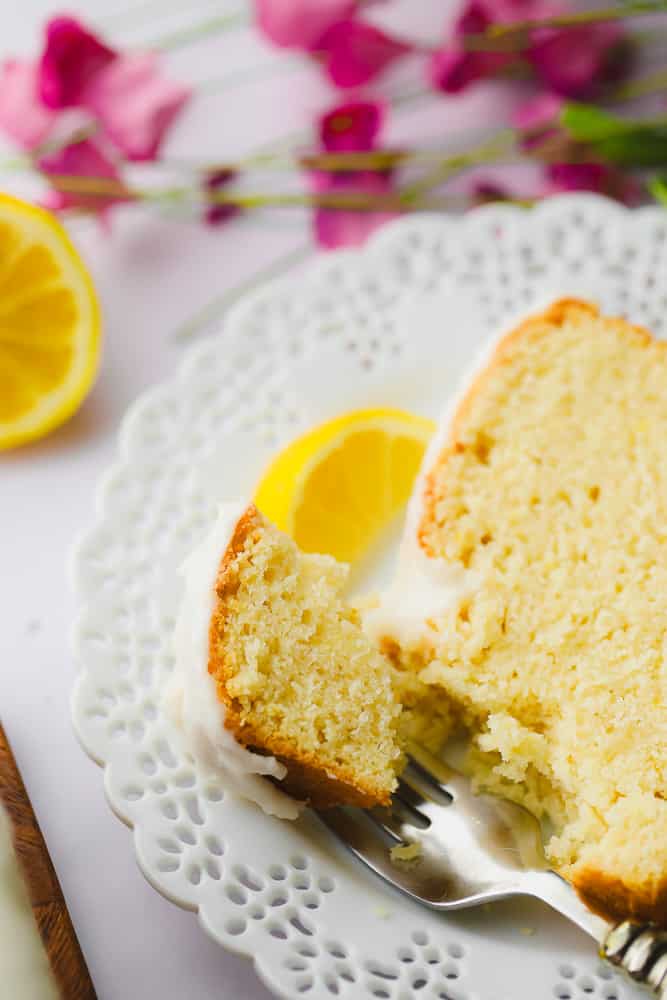 a fork taking a bite out of vegan pound cake on a white plate.