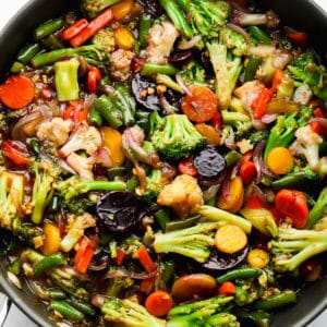 close up on sauce-covered cooked vegetables in a large black skillet.