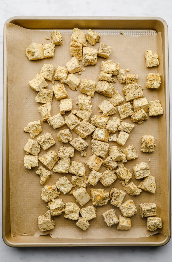 tofu in chunks with seasoning on parchment lined pan