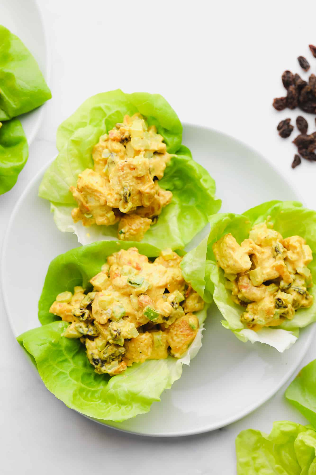 3 lettuce cups filled with tofu salad on a white plate.