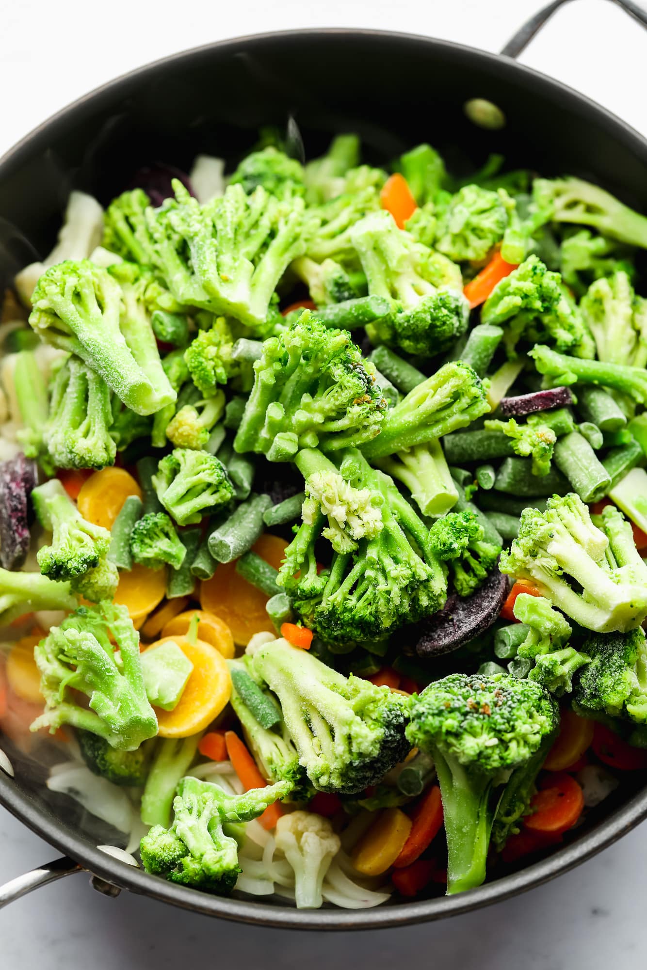 frozen vegetables in a large black skillet.