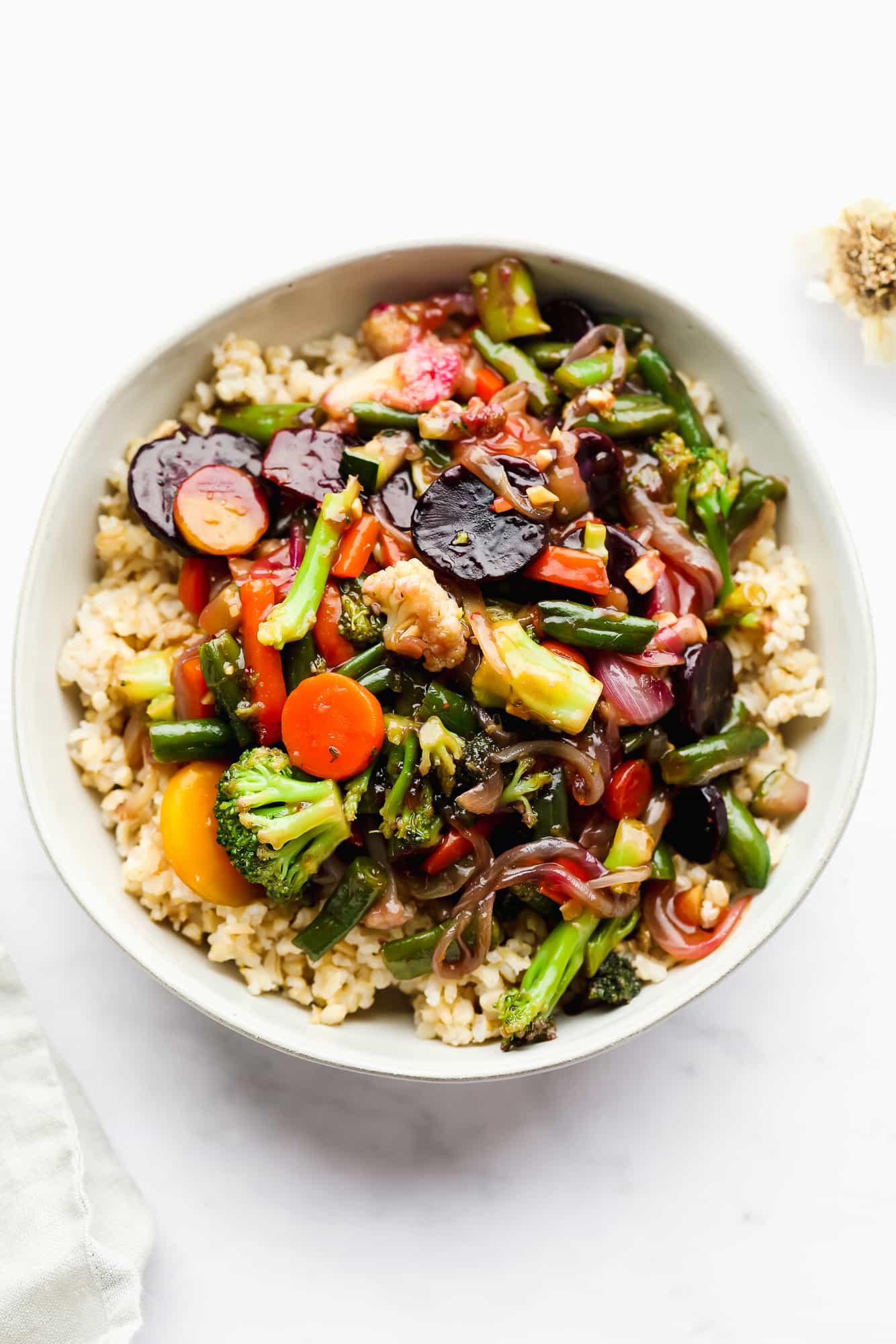 sauce-covered cooked vegetables over rice in a white bowl.