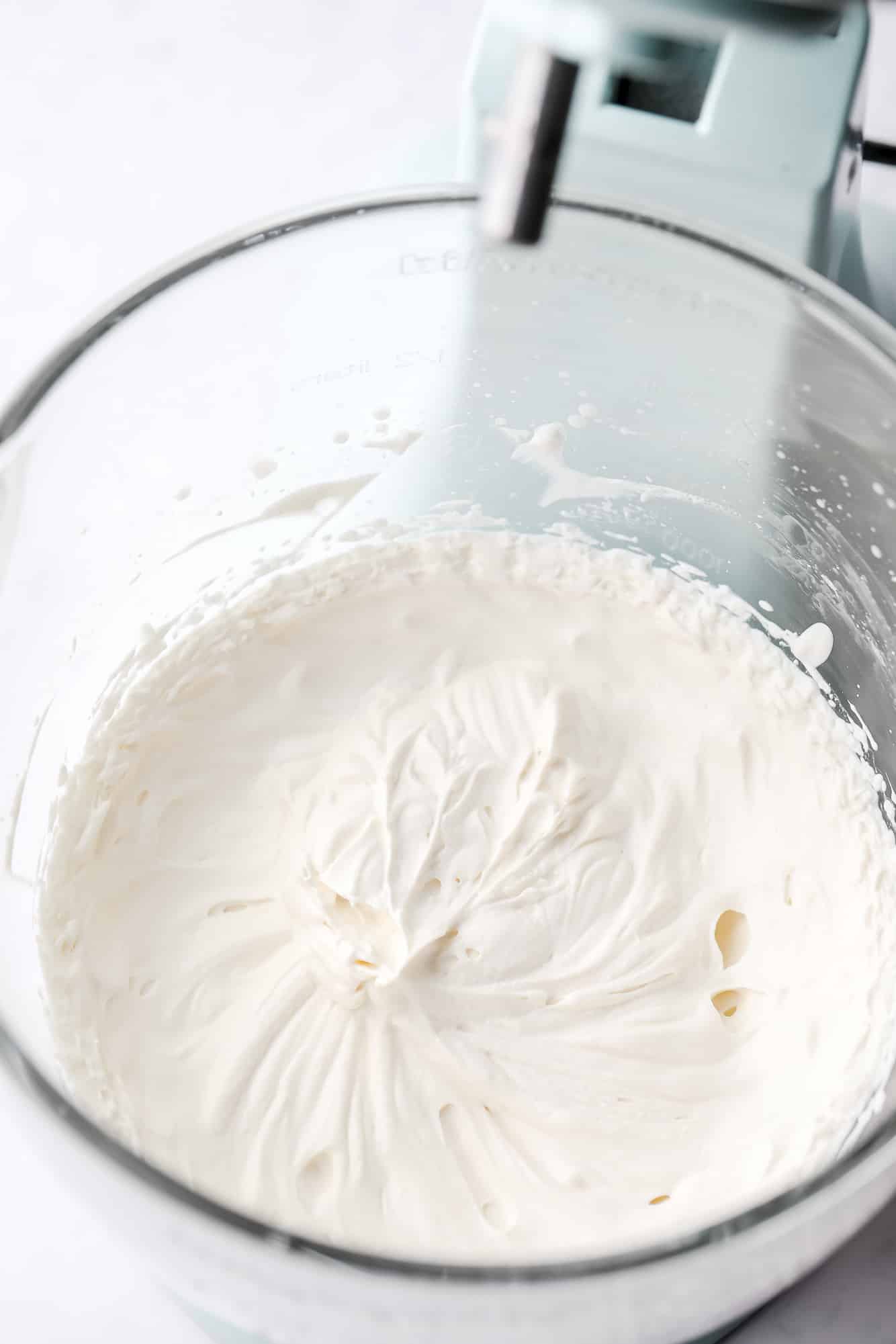 vegan whipped cream in the glass bowl of a standing mixer.