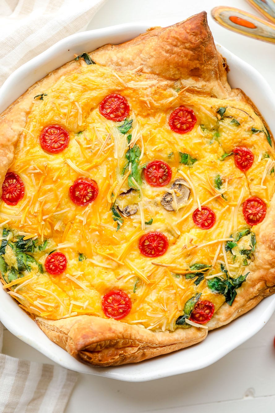 Close up on a baked JUST Egg quiche in a white pie plate.