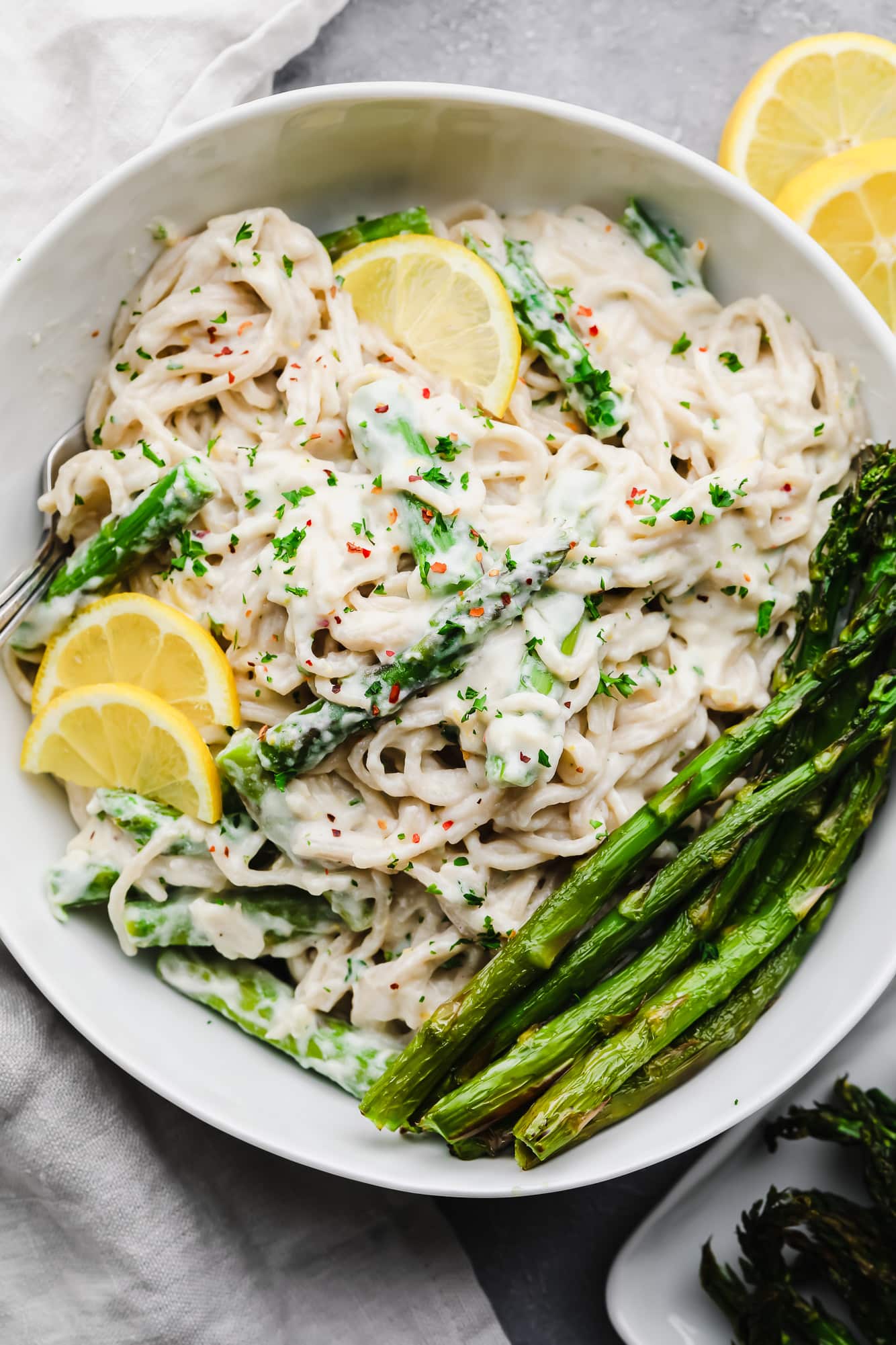 lemon asparagus pasta topped with cooked asparagus and lemon slices in a white bowl.