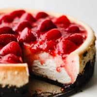 close up of a vegan strawberry cheesecake with a slice cut out.