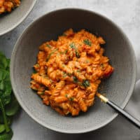 vegan tomato sauce-covered pasta in a grey bowl.
