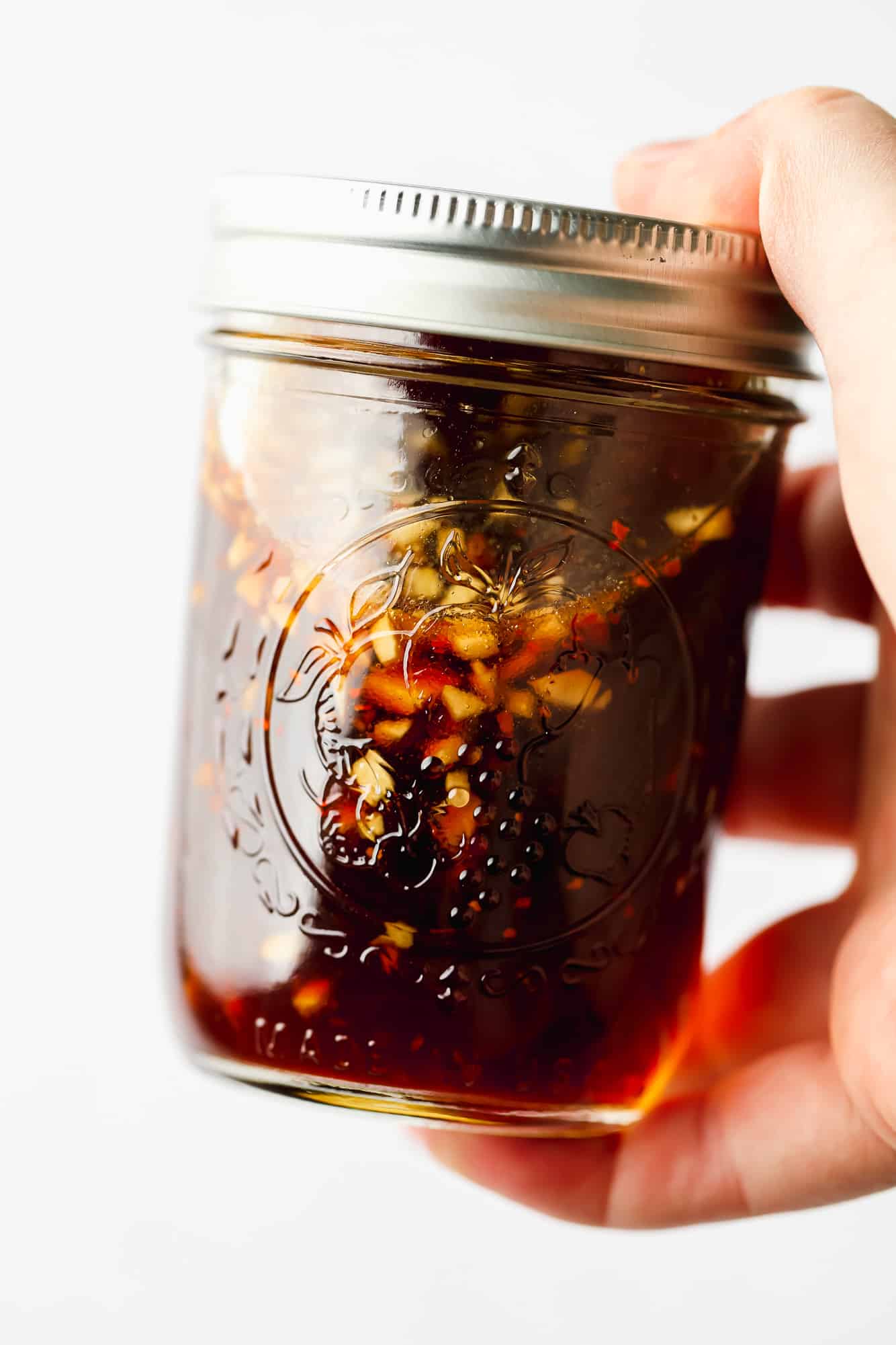 womans hand holding a jar of stir fry sauce.