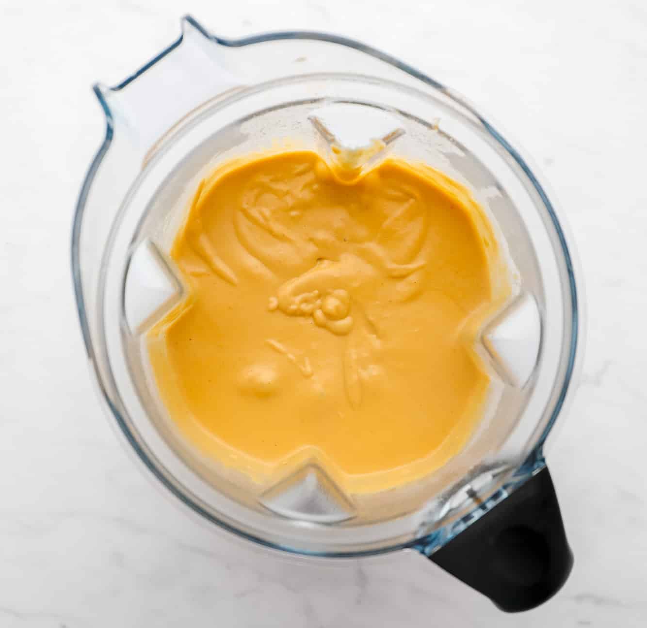 A creamy, yellow, blended mixture in a large blender.