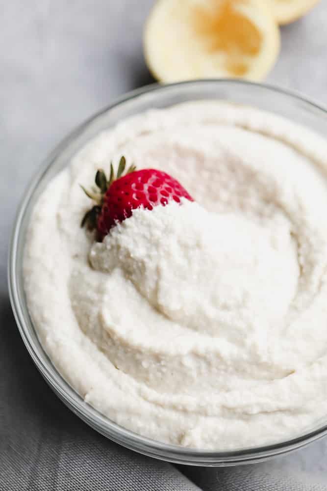 glass bowl filled with vegan mascarpone cheese and a strawberry