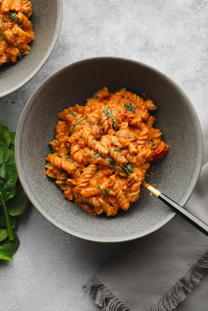 vegan tomato sauce-covered pasta in a grey bowl.