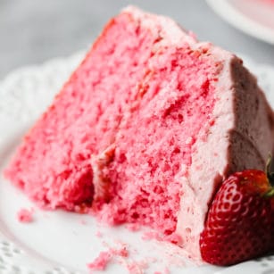 square image of a piece of pink cake with a strawberry on the side