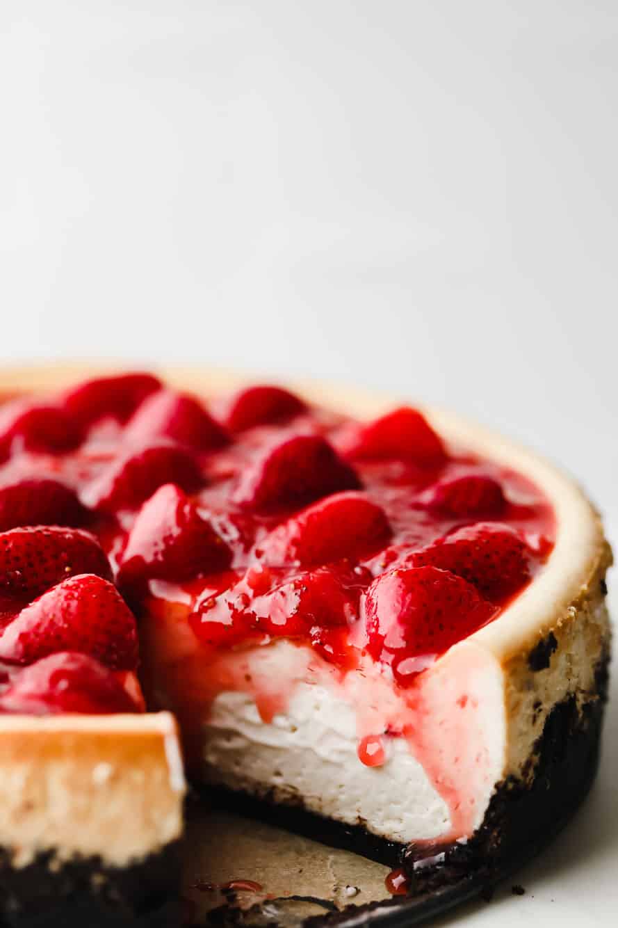 vegan strawberry cheesecake with a slice cut out.