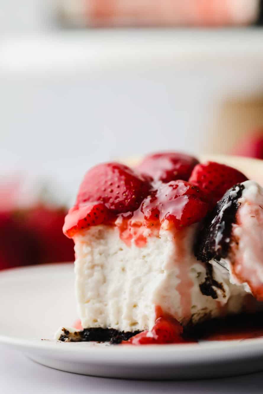 close up on a slice of vegan strawberry cheesecake with a bite missing.