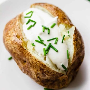 square image of a baked potato with vegan sour cream and chives