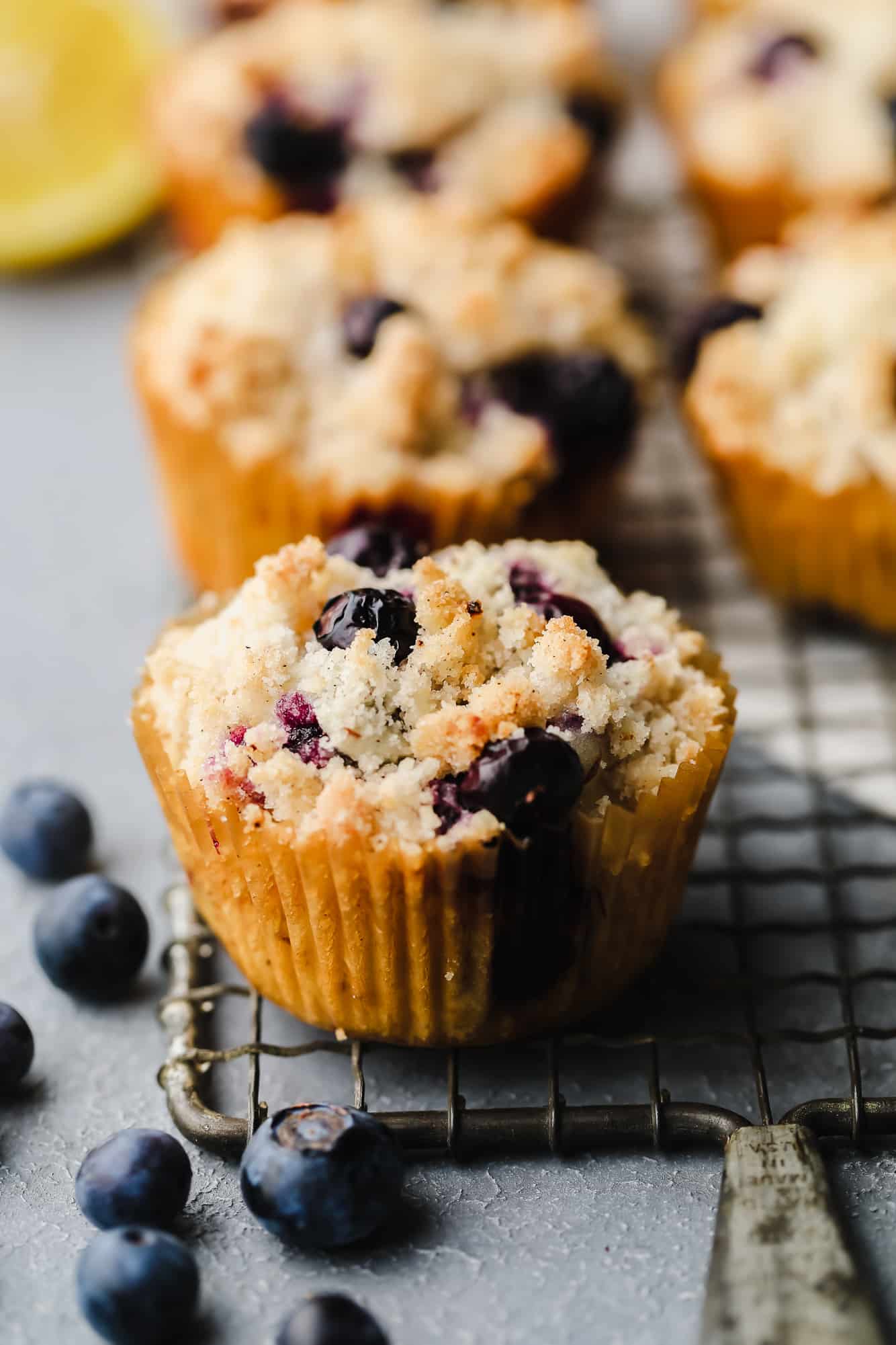 close up on a baked gluten free blueberry muffin on a wire rack.