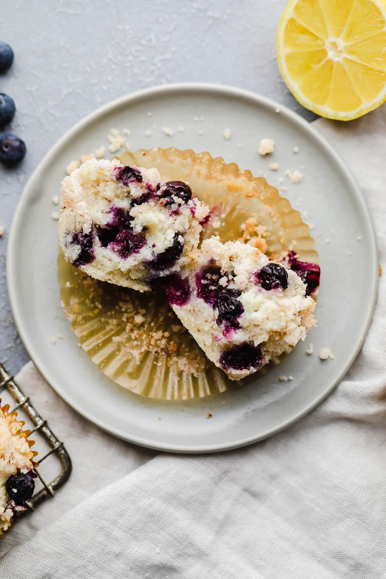 a gluten free blueberry muffin cut in half on a small white plate.