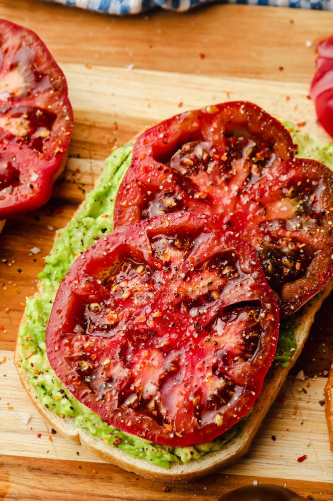 piece of vegan avocado toast with huge slices of tomato