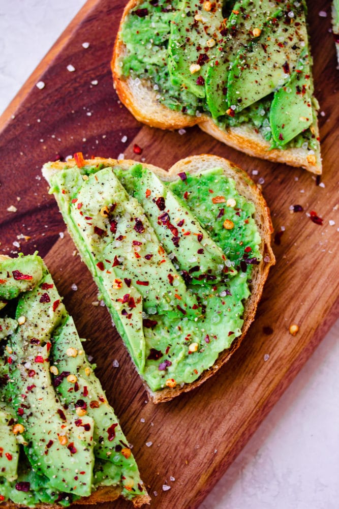 avocado toast on cutting board with red chili flakes