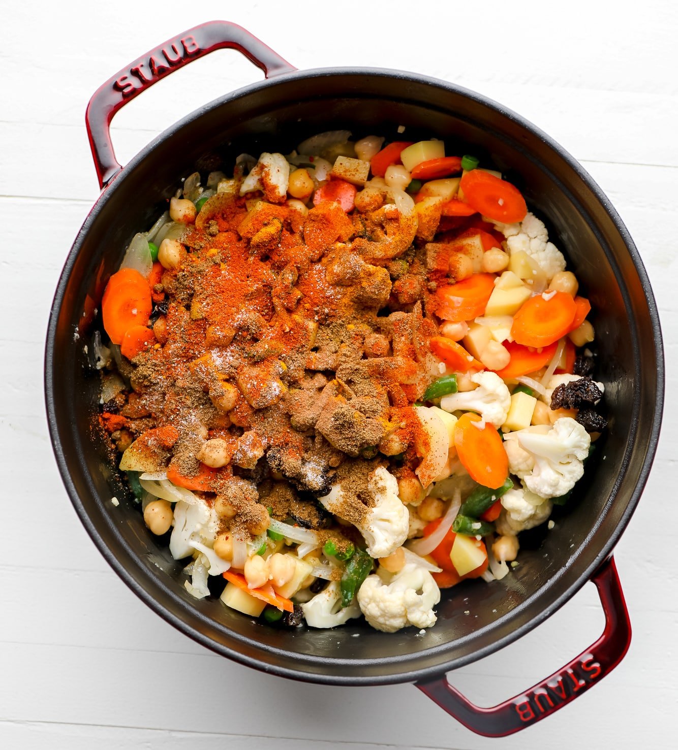 Vegetables and spices in a large black pot.