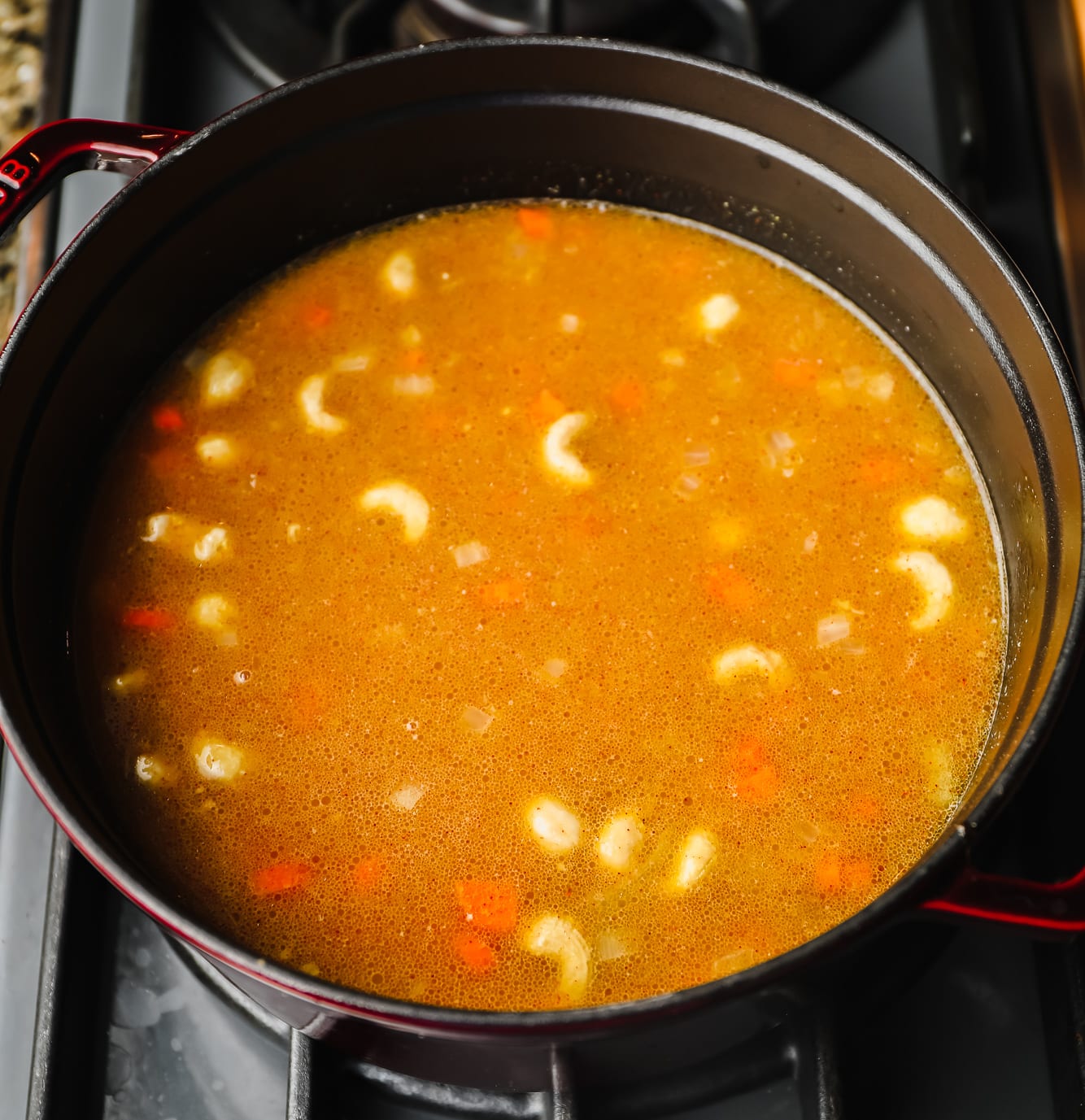 cooking broccoli cheddar soup in a large black pot.