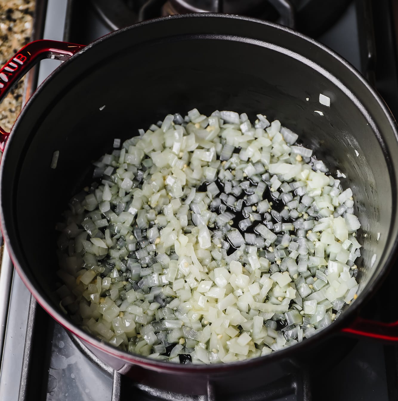 sauteeing chopped onion and garlic in a large black pot.