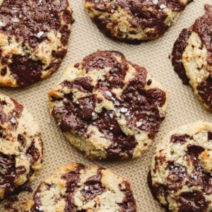 close up of baked almond flour chocolate chip cookies on a lined baking sheet.