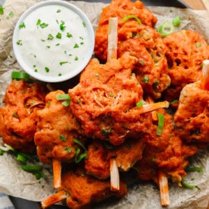 close up on a pile of vegan wings next to a small bowl filled with white dipping sauce.