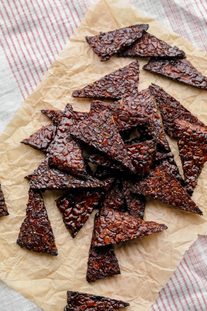 lots of cooked protein triangles on parchment paper with red striped towel