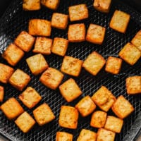 cooked tofu cubes in an air fryer basket.