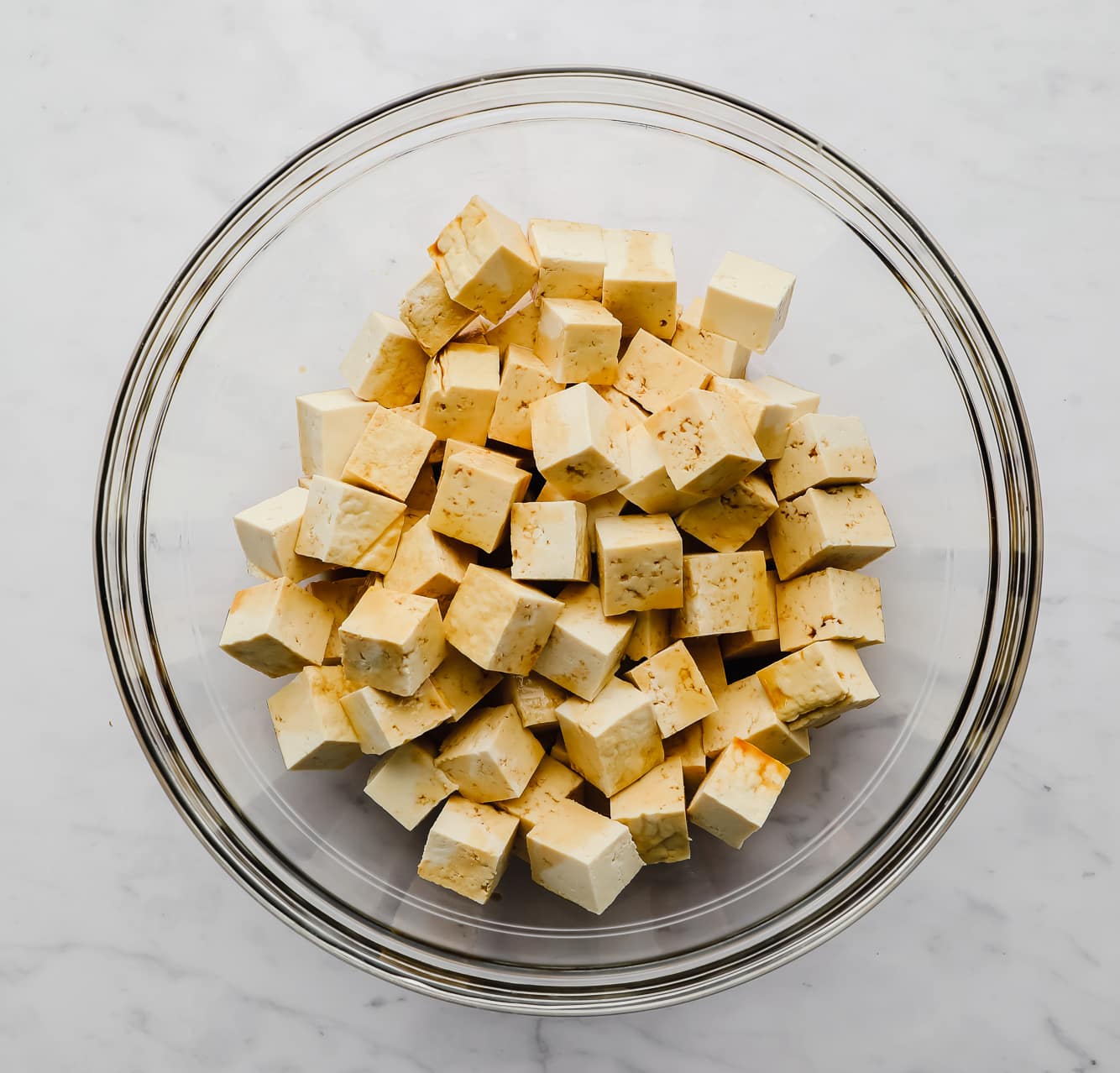 tofu cubes drizzled with soy sauce in a large glass bowl.