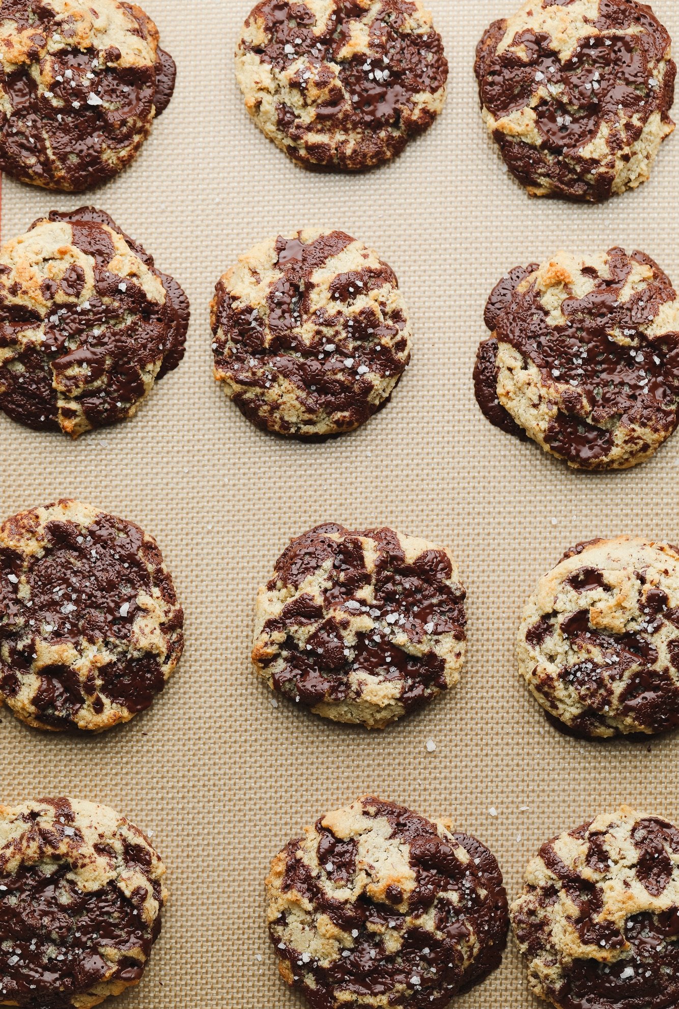 rows of baked almond flour chocolate chip cookies on a lined baking sheet.