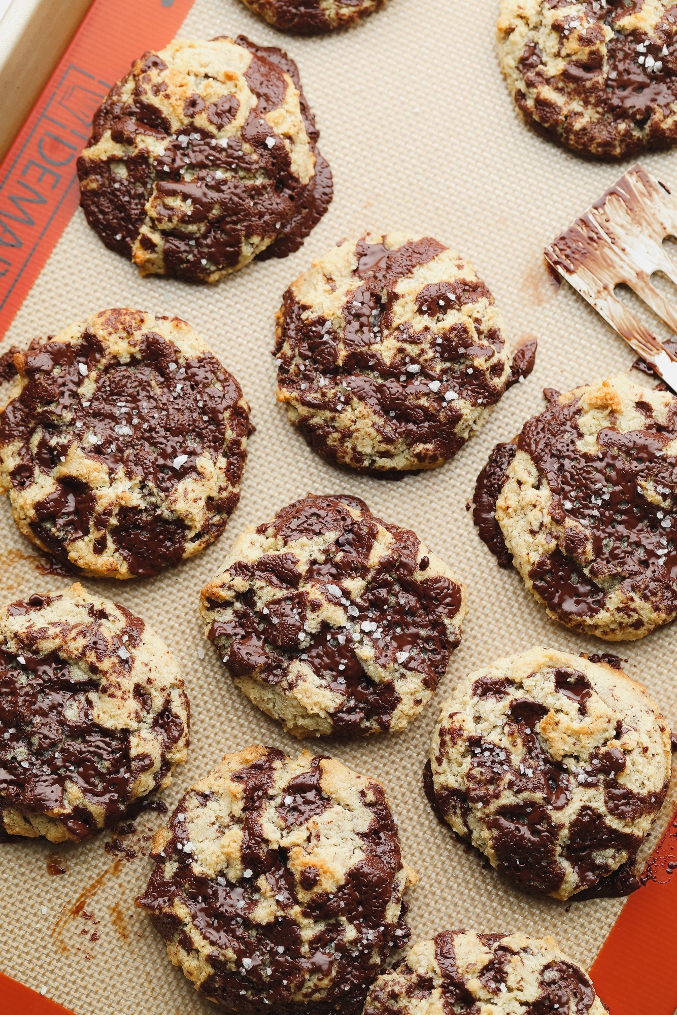 rows of baked almond flour chocolate chip cookies on a lined baking sheet.