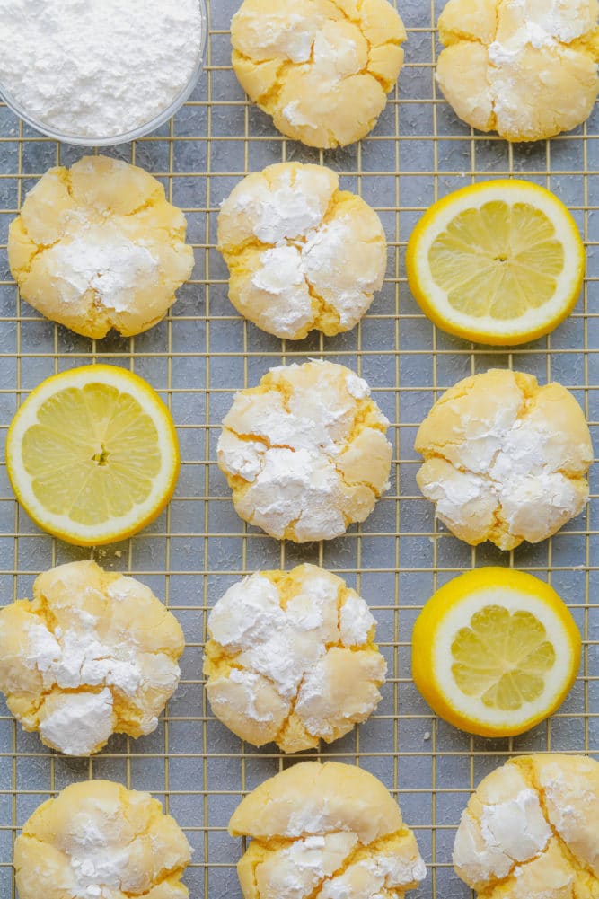many lemon crinkle cookies on a baking sheet with grey background