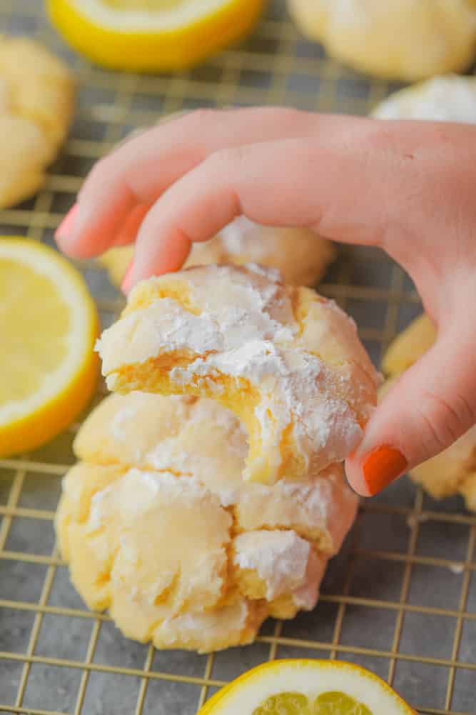 hand picking up a yellow cookie from stack of others on cooling rack