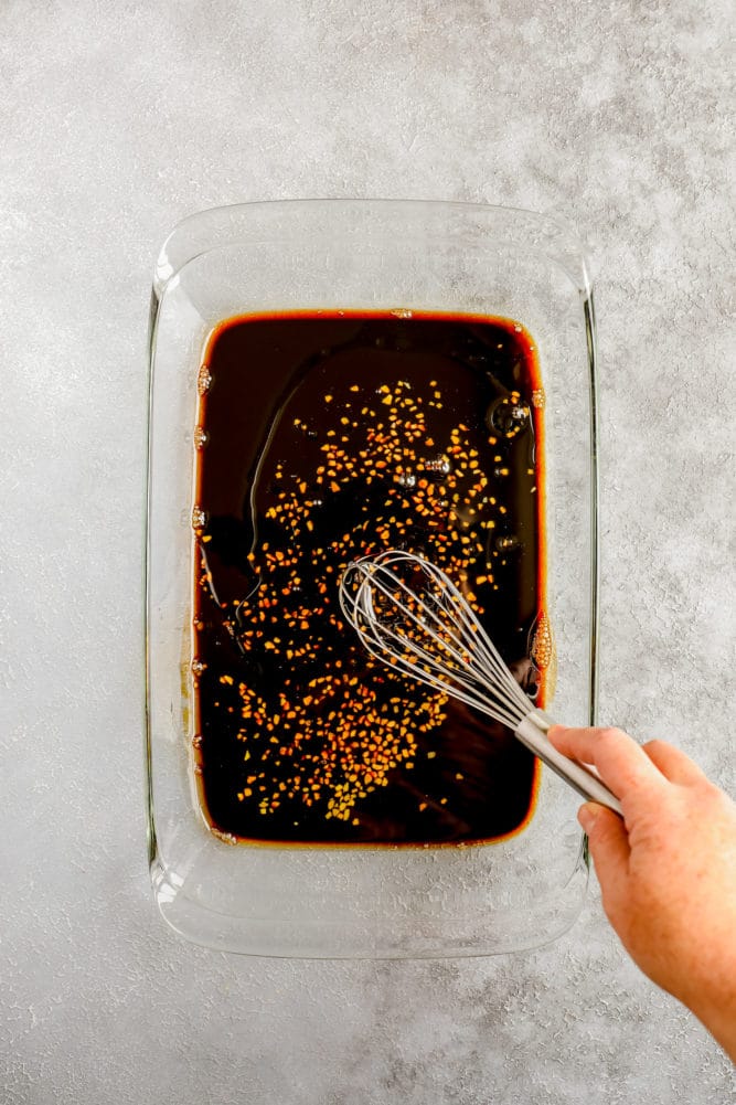 sauce being whisked with garlic in a glass dish