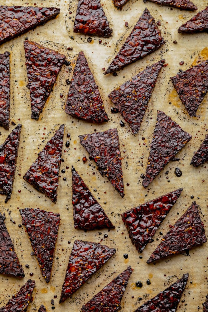 lots of triangle marinated tempeh pieces, cooked on parchment paper