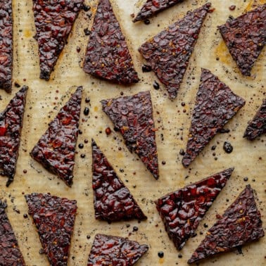 lots of triangle tempeh pieces on parchment paper, cooked