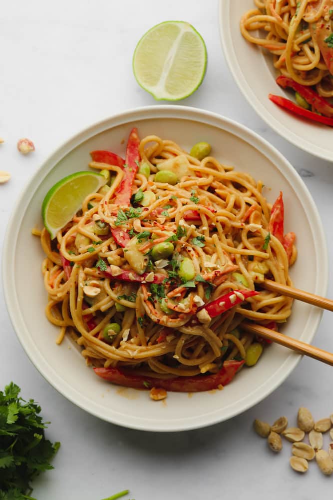 two bowls full of peanut noodles with vegetables