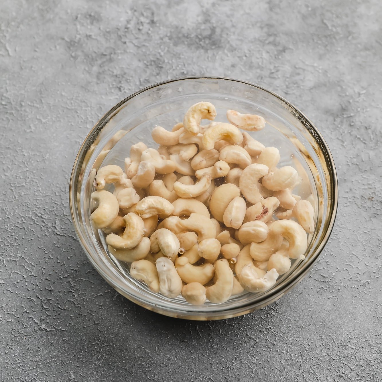 cashews soaking in a glass bowl filled with water.