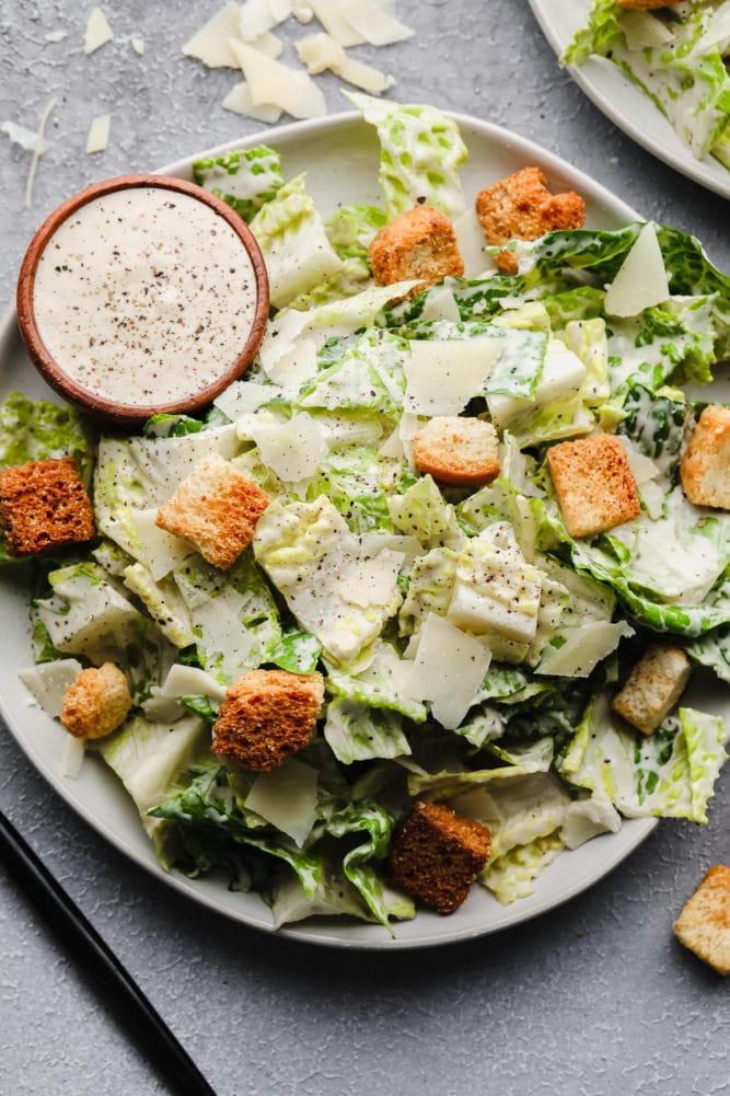 close up of a vegan caesar salad with croutons, lettuce, dressing and parmesan shaves