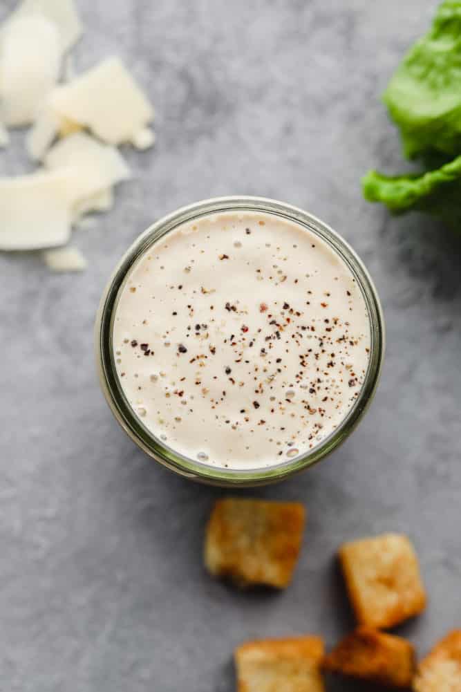 creamy white dressing with black pepper in glass dish with grey background