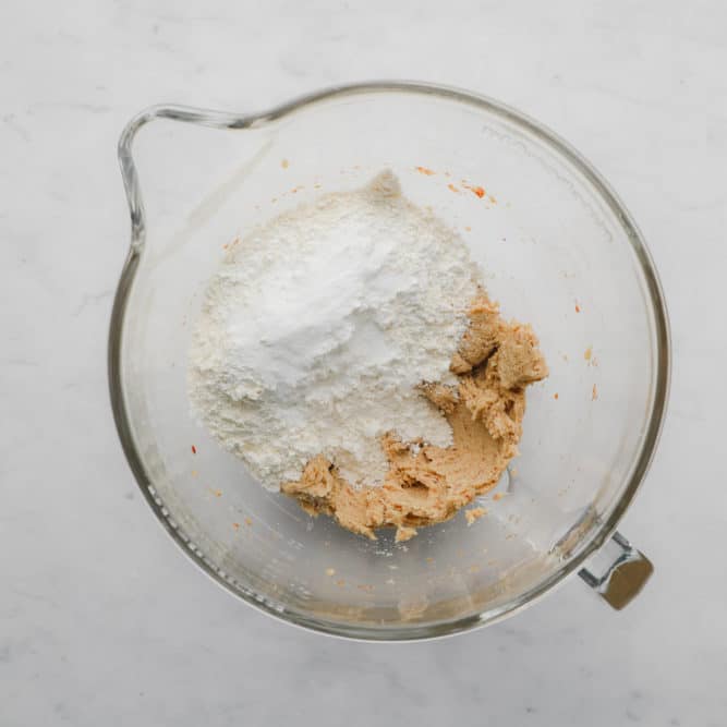 glass mixing bowl with dry ingredients being added to wet for cookies