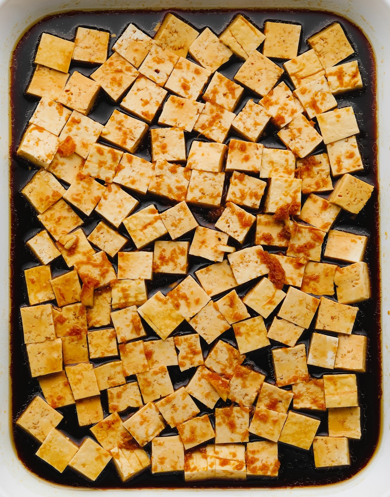 tofu cubes sitting in a dark brown marinade.