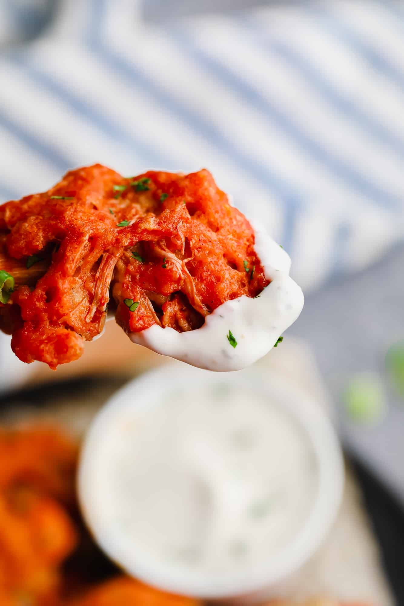 close up on a vegan wing dipped in white dipping sauce.