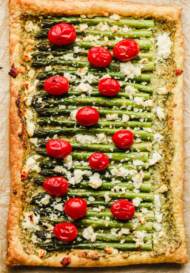 whole asparagus puff pastry tart on parchment paper, baked with feta