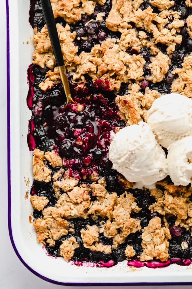 rectangle dish of blueberry crisp with scoops of ice cream