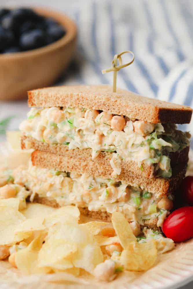 chickpea salad sandwich with bowl of blueberries in background