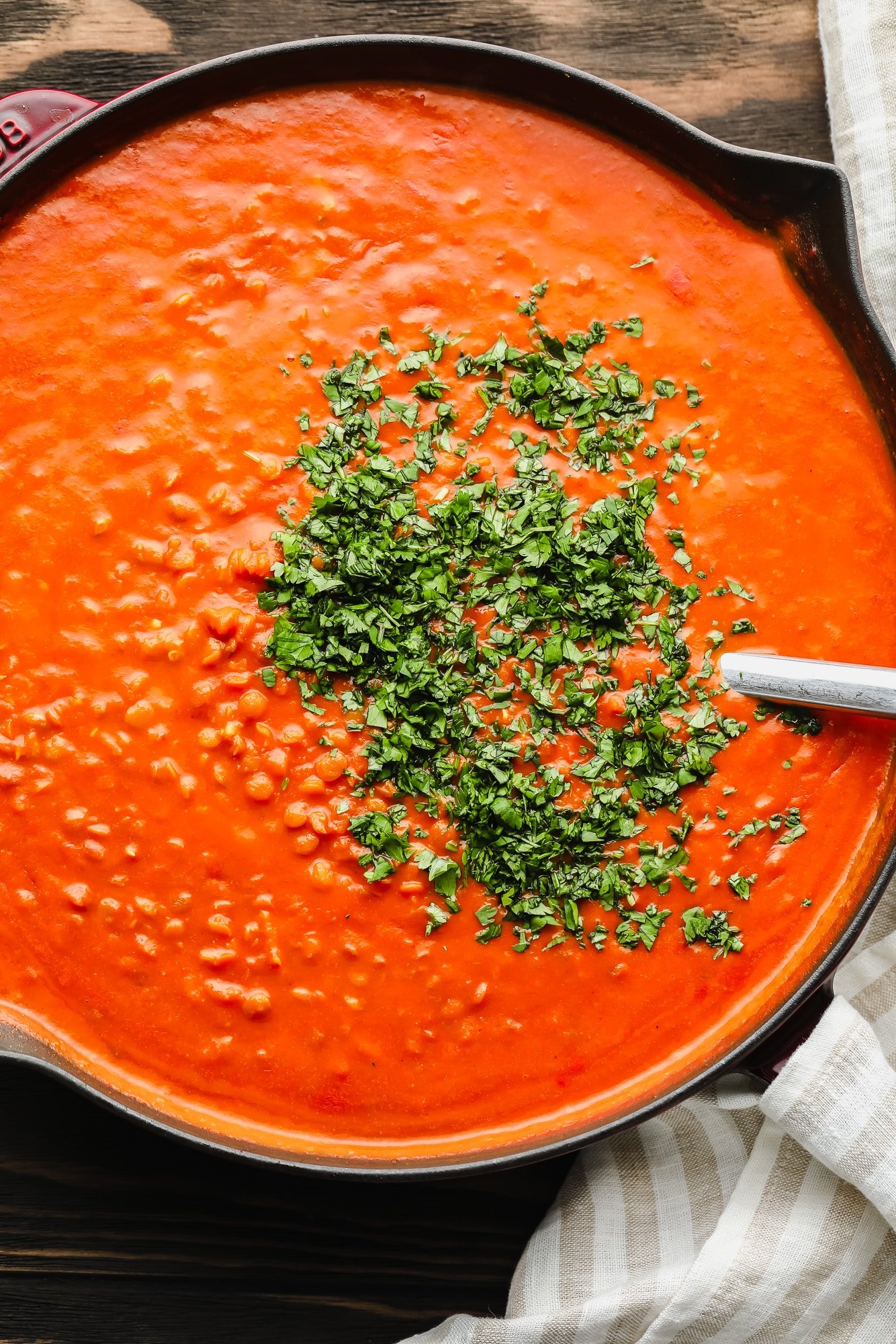 lentil curry topped with chopped cilantro leaves in a large black pot.